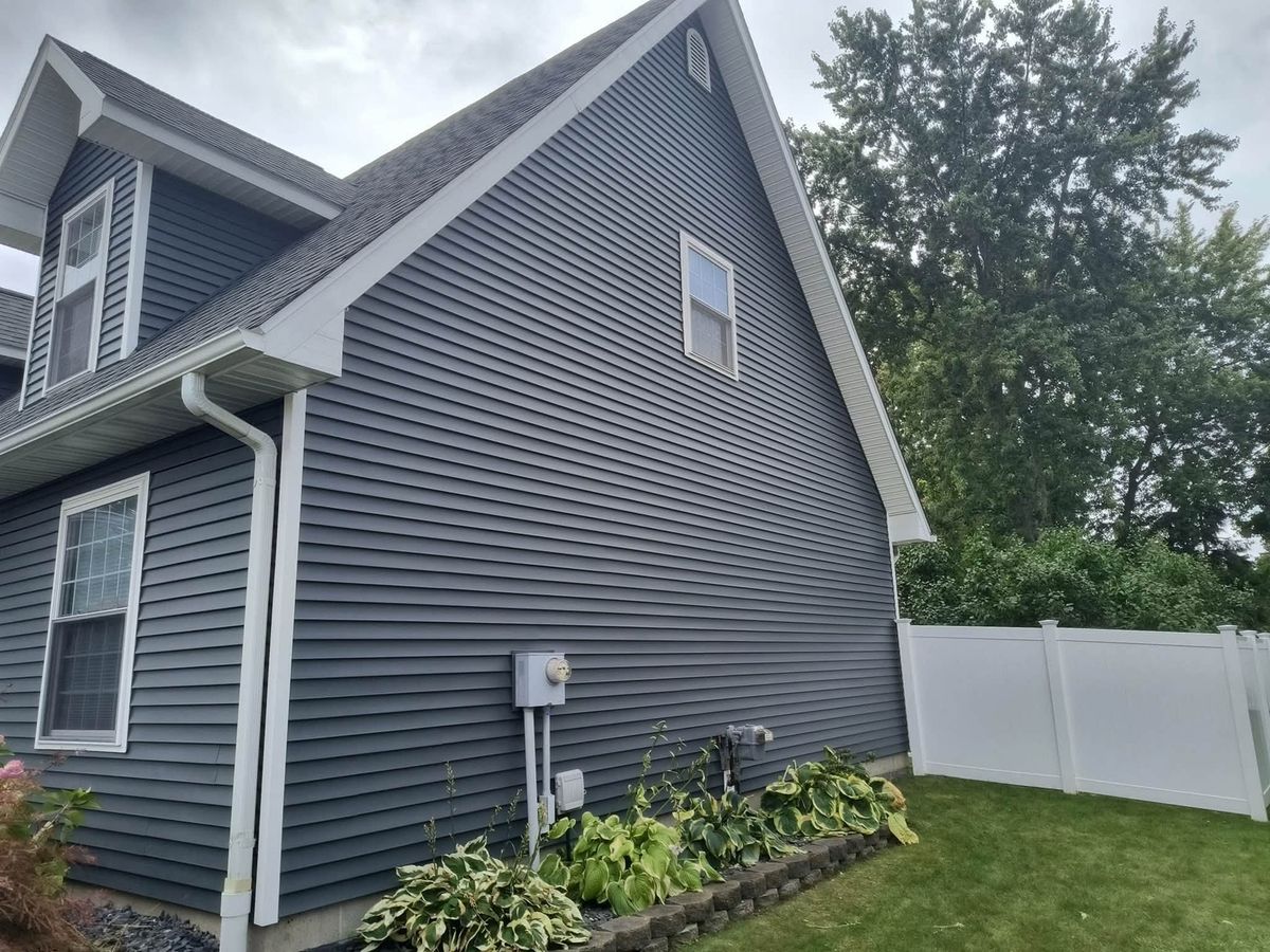Slate gray vinyl siding on a two-story house gable with a dormer window and white trim