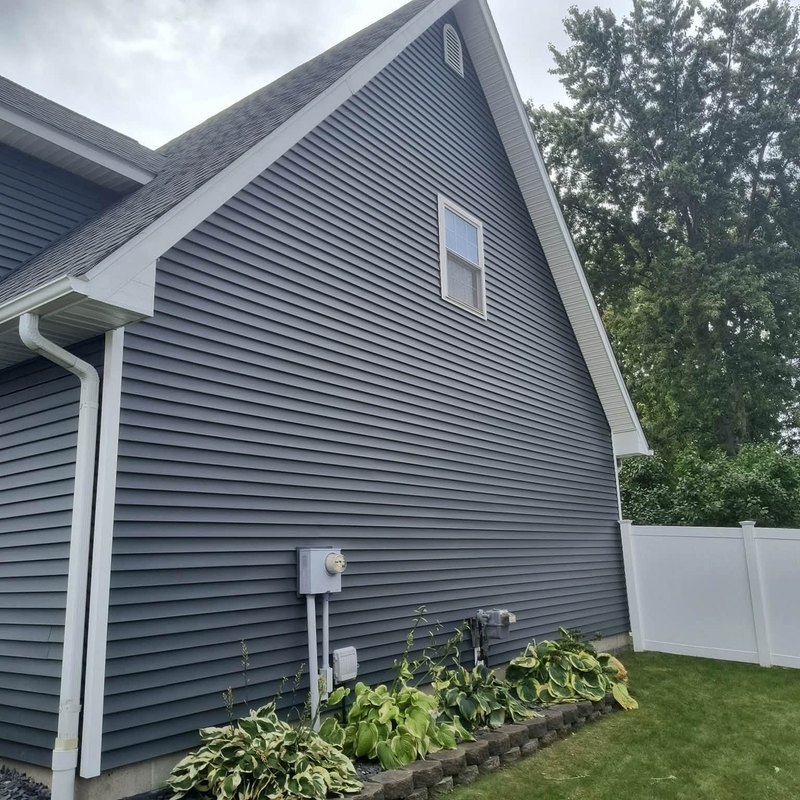 Slate gray vinyl siding on a two-story house gable with a window and white trim